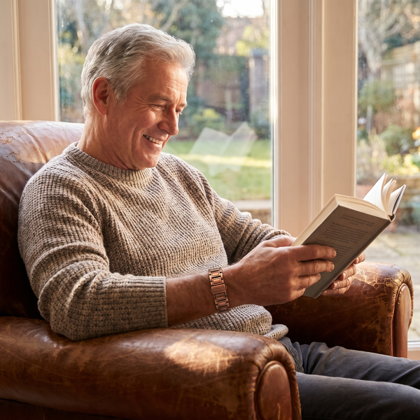 Man reading in an armchair wearing a copper bracelet